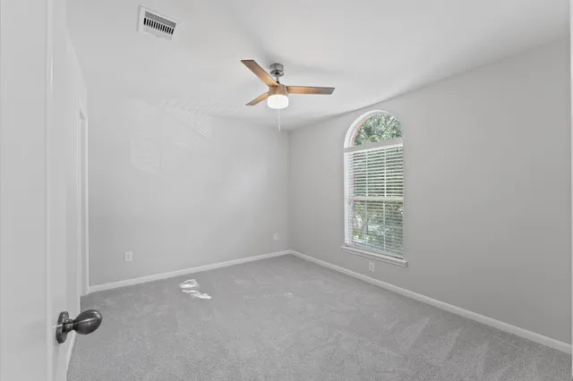 an empty room with windows and ceiling fan