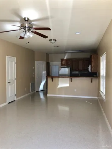 an empty room with windows and ceiling fan