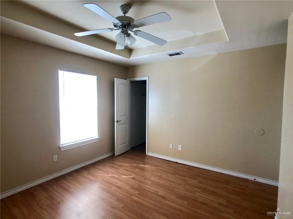 804 North Taylor Road, Unit 29 Mission, TX 78572 - Photo 23 of 27 an empty room with wooden floor chandelier fan and windows