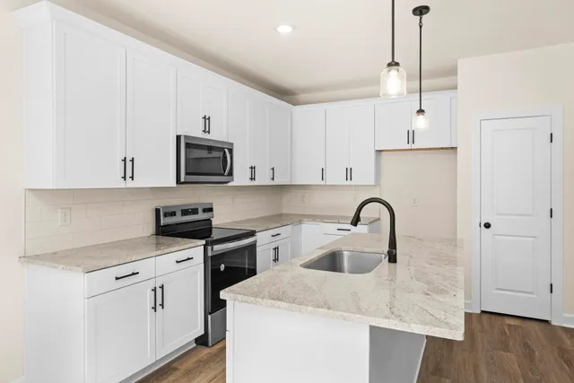a kitchen with granite countertop a sink a stove and cabinets