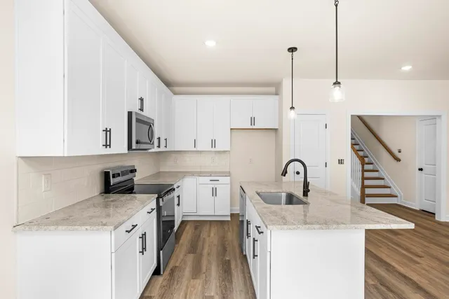 a kitchen with a sink a kitchen island a stove and wooden floor