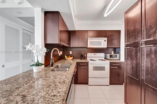 a kitchen with granite countertop a sink a stove and cabinets