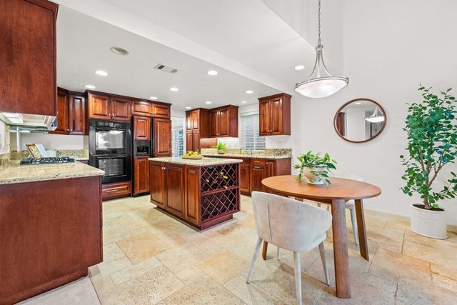 a kitchen with stainless steel appliances granite countertop wooden cabinets and a refrigerator