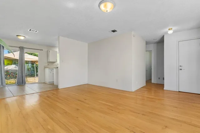 a view of an empty room with wooden floor and a window