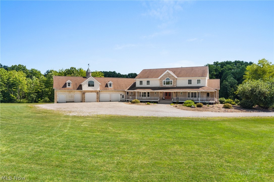 9419 Robinson Road Chardon, OH 44024 - Photo 36 of 49 Expansive property featuring a multi-car garage with dormer windows and cupola, a gravel driveway, a large front lawn, a wrap-around porch, and stone facade accents