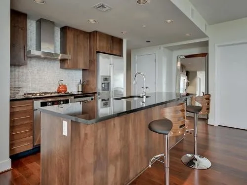 a kitchen with stainless steel appliances granite countertop a sink a stove and chairs with wooden floor