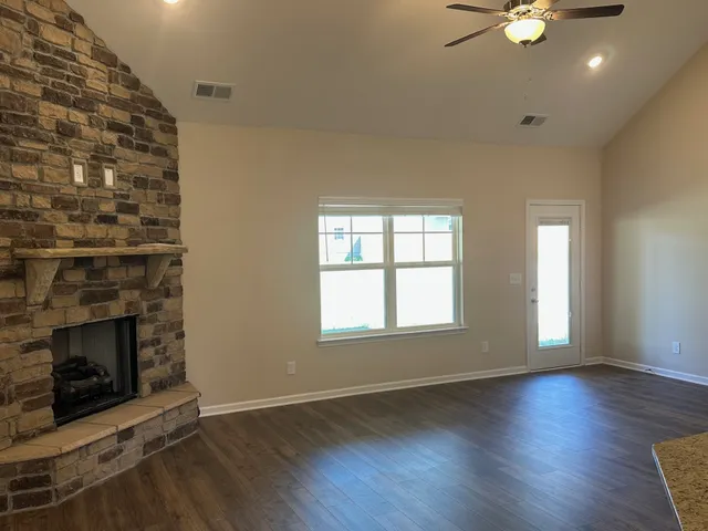 an empty room with wooden floor fireplace and windows