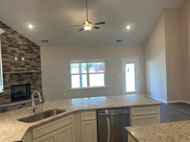 a kitchen with granite countertop a sink a counter space appliances and cabinets