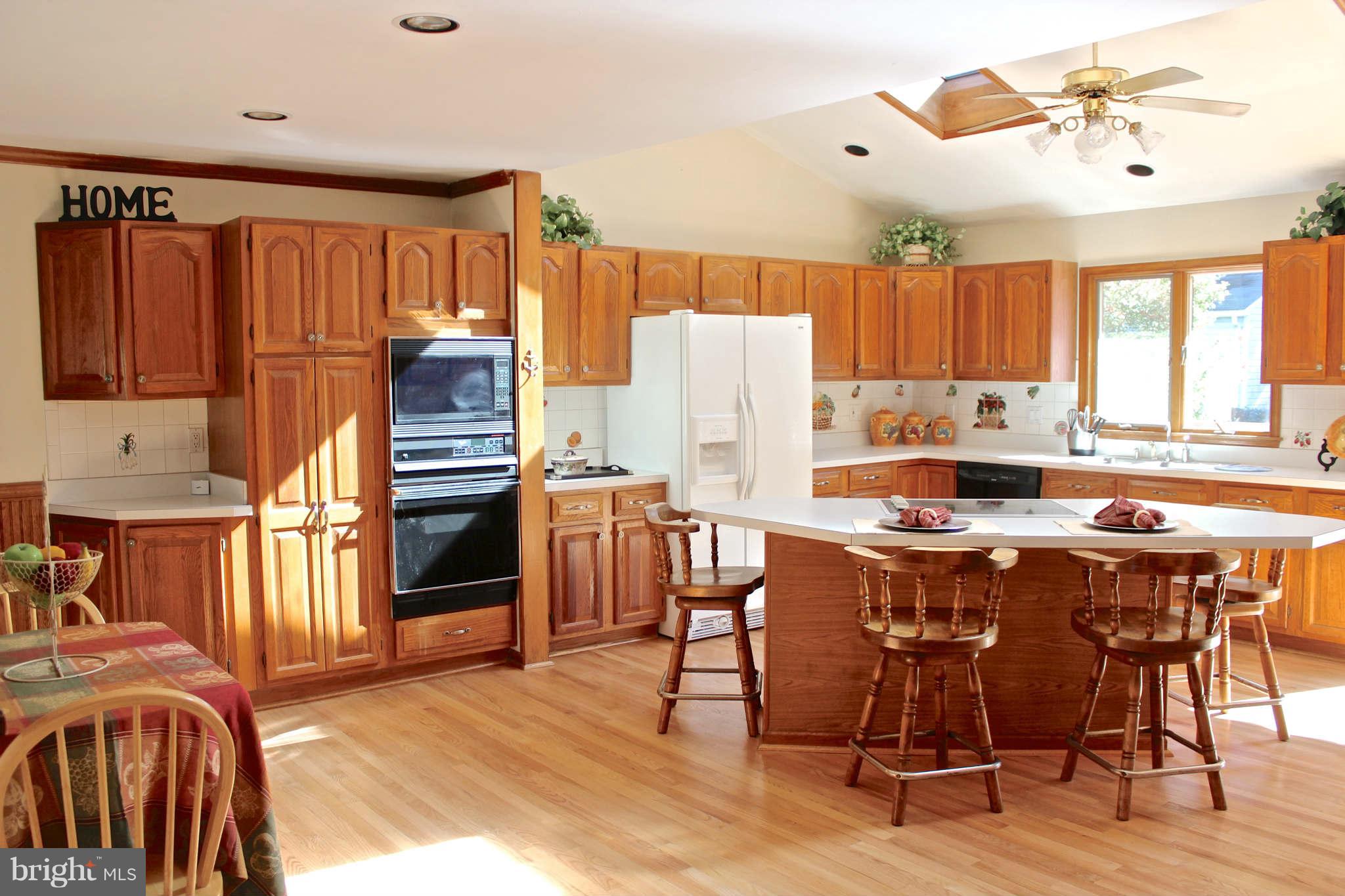 3697 Altondale Road Reisterstown, MD 21136 - Photo 5 of 21 a kitchen with stainless steel appliances granite countertop a refrigerator a stove a sink dishwasher and white countertops with wooden floor