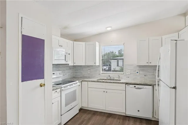 a kitchen with white cabinets appliances and a window