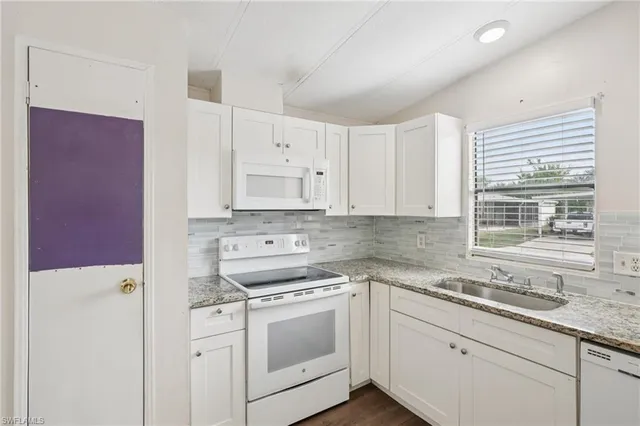 a kitchen with granite countertop white cabinets and white appliances