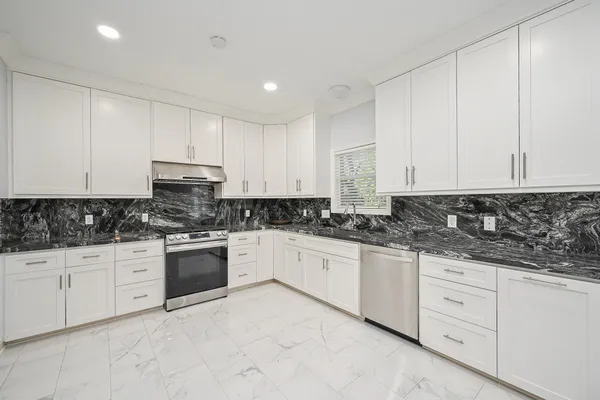 a kitchen with granite countertop white cabinets and stainless steel appliances