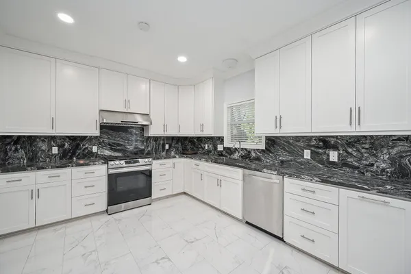 a kitchen with granite countertop white cabinets and stainless steel appliances