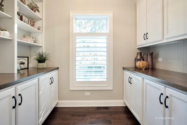 a kitchen with white cabinets and window