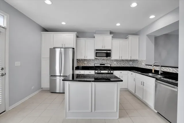 a kitchen with white cabinets and stainless steel appliances