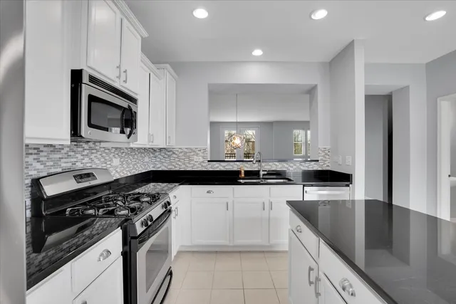 a kitchen with granite countertop a sink dishwasher stove and microwave with wooden cabinets