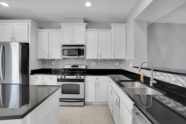 a kitchen with granite countertop a sink stove and refrigerator