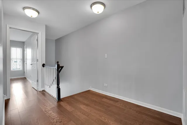 an empty room with wooden floor and a hallway