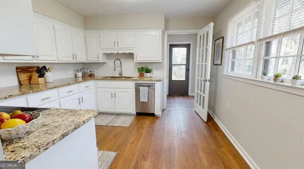 a kitchen with a hard wood floor white cabinets and white appliances