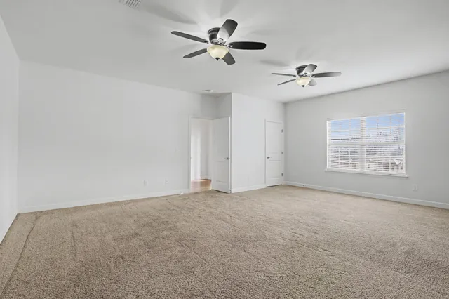 an empty room with fan and windows