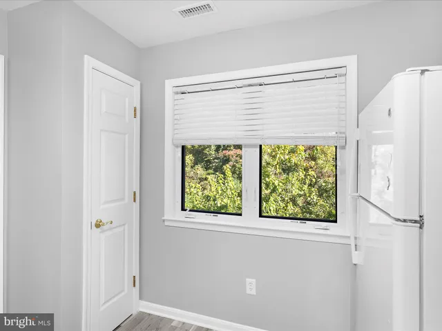 a bathroom with a window and a white refrigerator