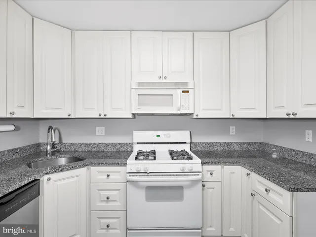 a kitchen with granite countertop white cabinets and white appliances