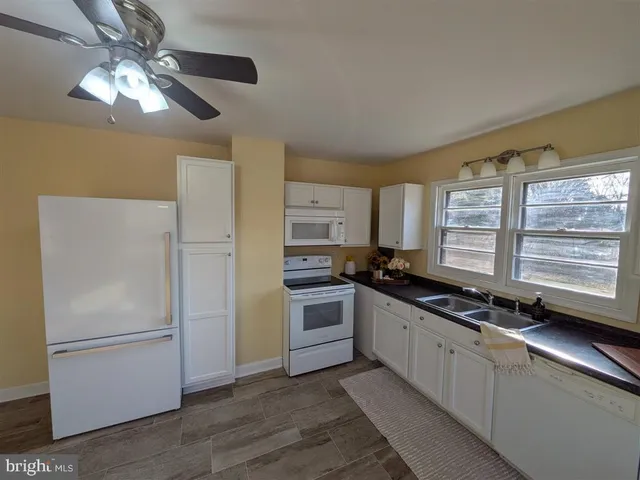 a kitchen with stainless steel appliances a refrigerator a stove a sink and white cabinets