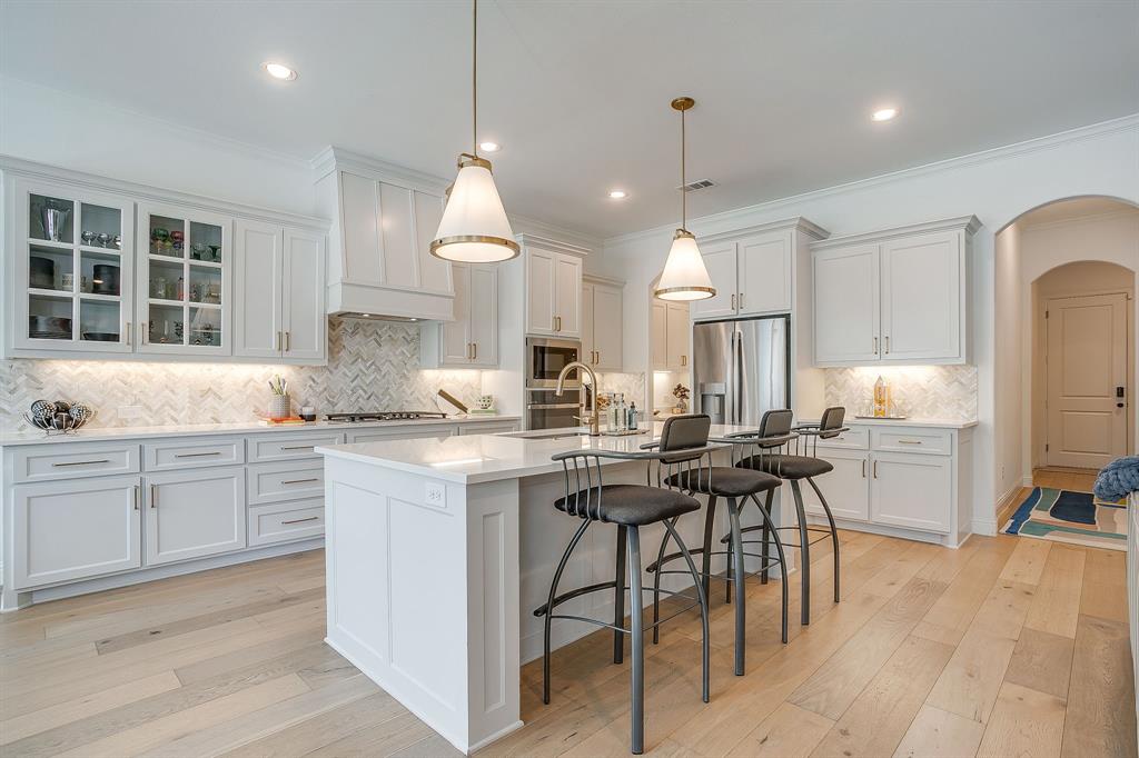 413 Kestrel Court Aledo, TX 76008 - Photo 13 of 40 a kitchen with stainless steel appliances granite countertop a stove a sink dishwasher a refrigerator and white cabinets with wooden floor