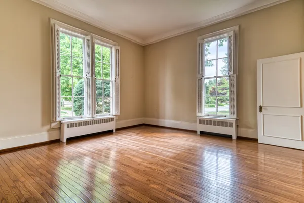 an empty room with wooden floor and windows