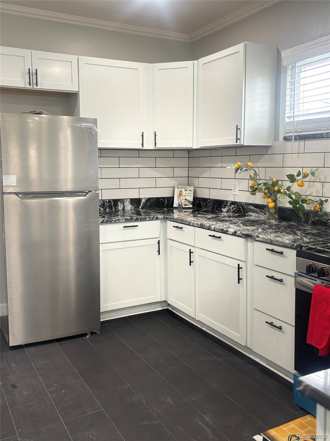 5012 Fischer Street Detroit, MI 48213 - Photo 5 of 22 Kitchen featuring stainless steel appliances, dark stone countertops, white cabinets, tasteful backsplash, and crown molding