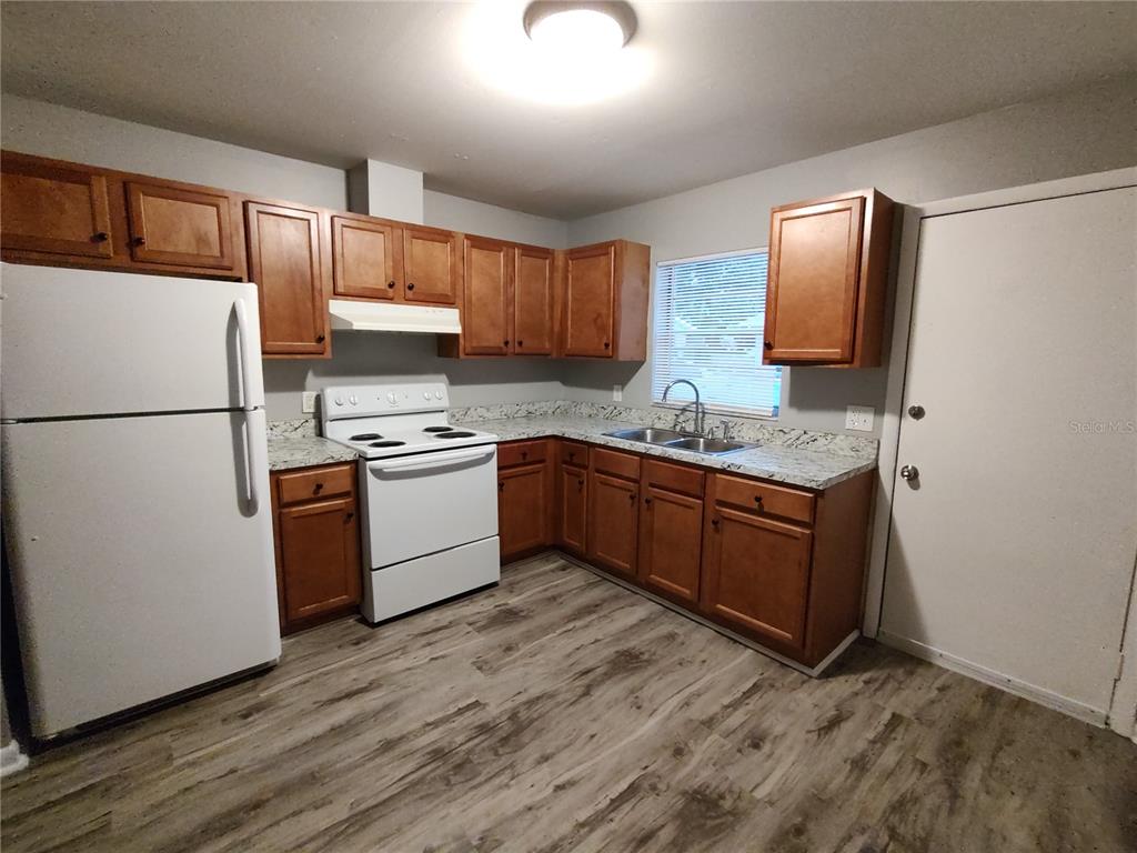 200 Church Street, Unit F2 Leesburg, FL 34748 - Photo 3 of 23 a kitchen with stainless steel appliances granite countertop a refrigerator sink and stove