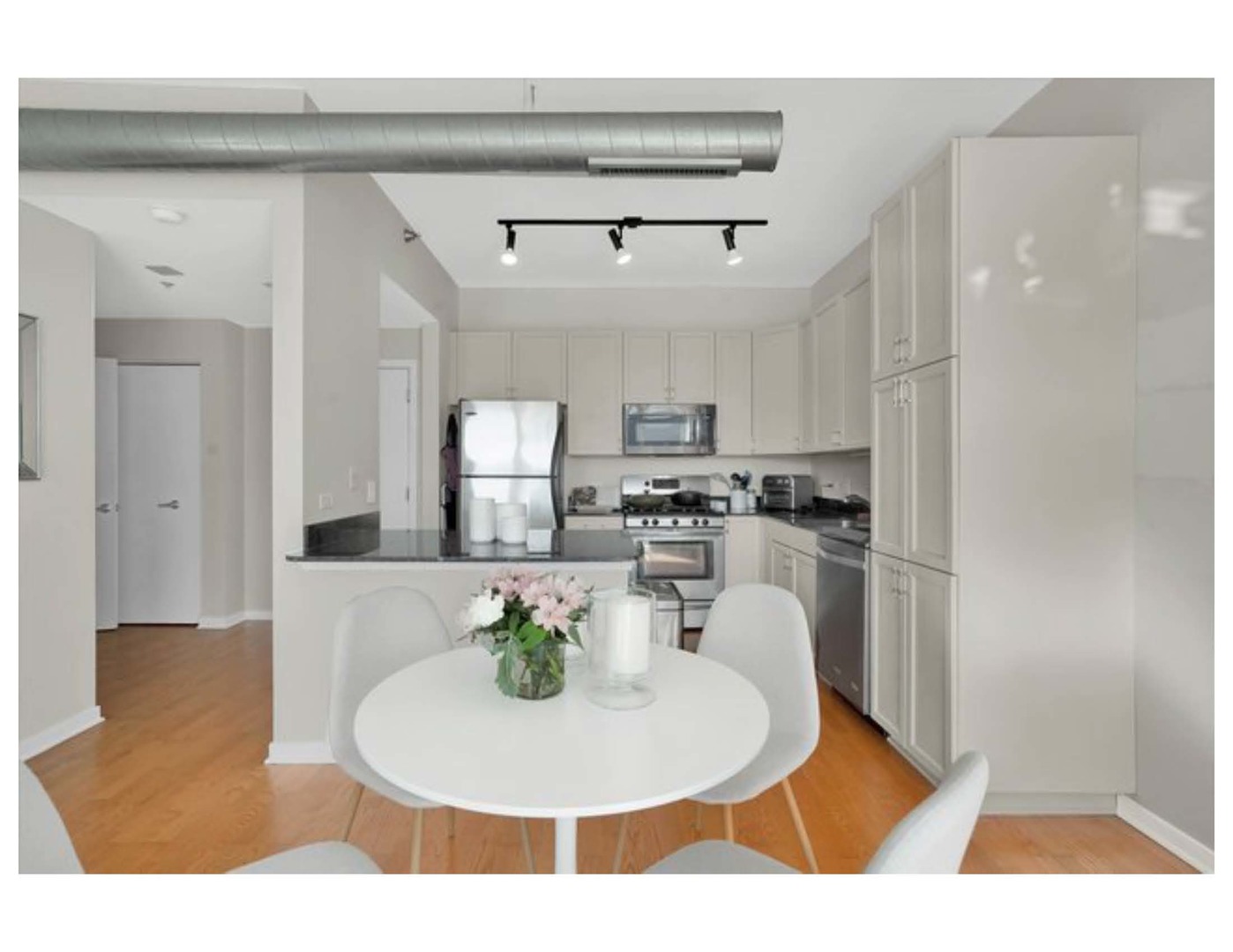 909 West Washington Boulevard, Unit 1002 Chicago, IL 60607 - Photo 3 of 15 a kitchen with stainless steel appliances granite countertop a refrigerator a sink a stove a dining table and chairs