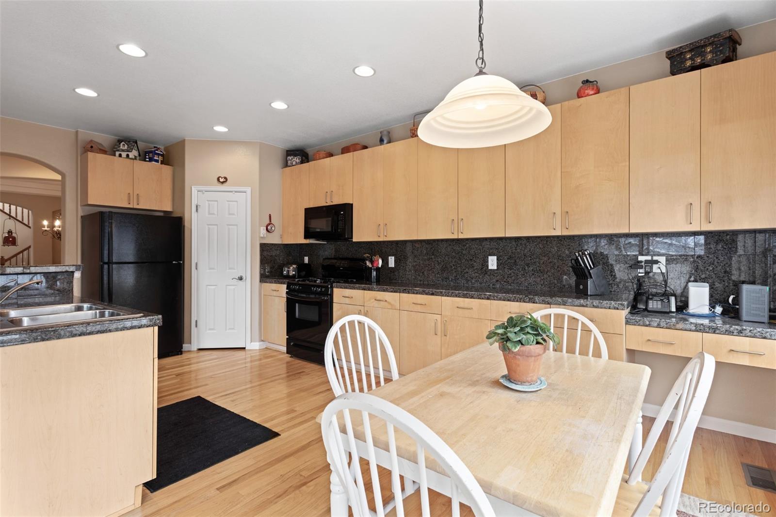 4207 Frederick Circle Longmont, CO 80503 - Photo 13 of 35 a kitchen with stainless steel appliances granite countertop a sink a stove a refrigerator a microwave oven with a dining table and chairs