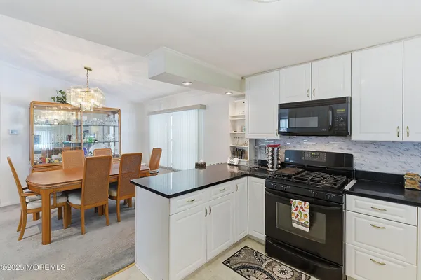 a kitchen with granite countertop a stove a sink a dining table and chairs