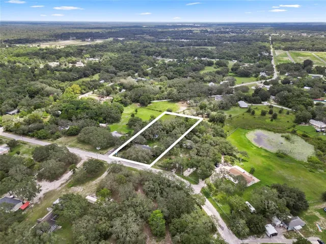 an aerial view of residential houses with outdoor space and trees