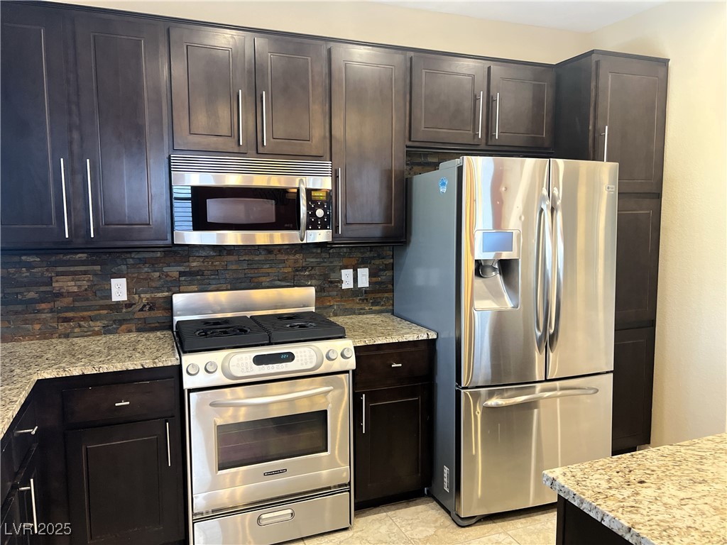 9535 Leaping Lizard Street Las Vegas, NV 89178 - Photo 2 of 37 Kitchen with backsplash, light stone countertops, and stainless steel appliances