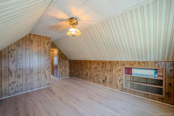 an empty room with wooden floor windows and fan