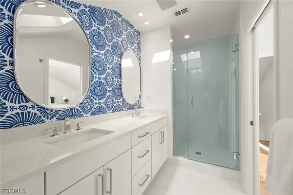 a bathroom with a double vanity sink mirror and shower