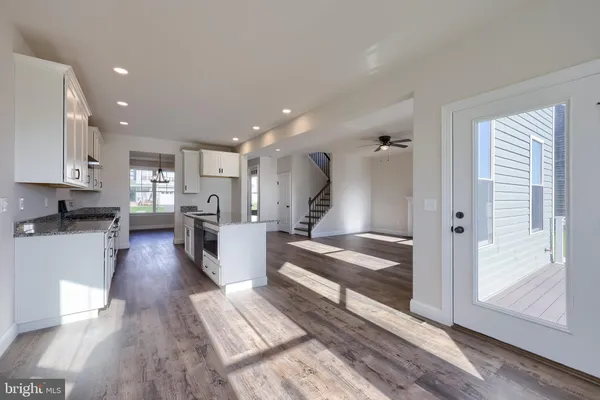 a view of a kitchen with kitchen island wooden floors appliances and a window
