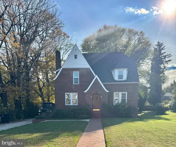 a front view of a house with a yard and a large tree