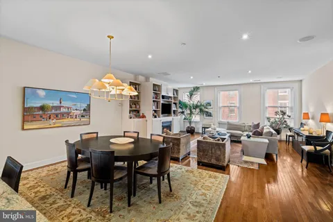 a view of a dining room and livingroom with furniture wooden floor a rug a painting and a chandelier