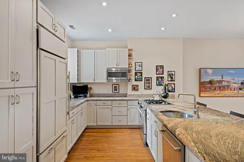 a large kitchen with stainless steel appliances granite countertop a sink stove and refrigerator