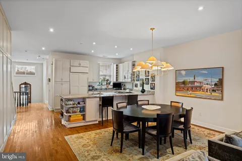 a dining room with stainless steel appliances granite countertop a dining table and chairs with wooden floor