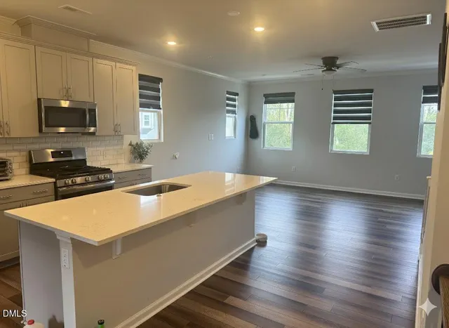 a large kitchen with kitchen island a sink dishwasher a stove and a microwave oven with wooden floor