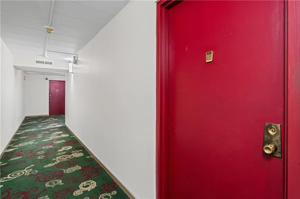 a view of a livingroom with a red wall & staircase