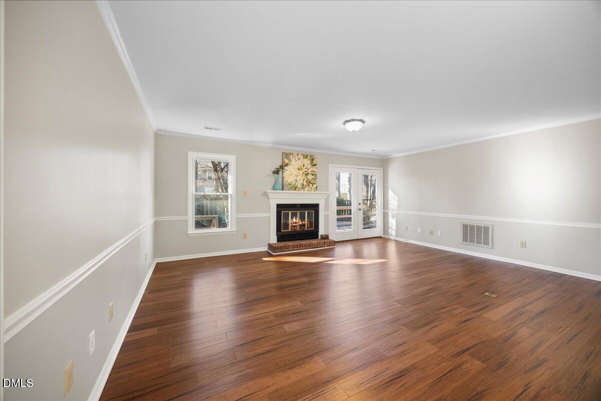 1511 Hemphill Drive Raleigh, NC 27609 - Photo 11 of 37 an empty room with wooden floor fireplace and windows