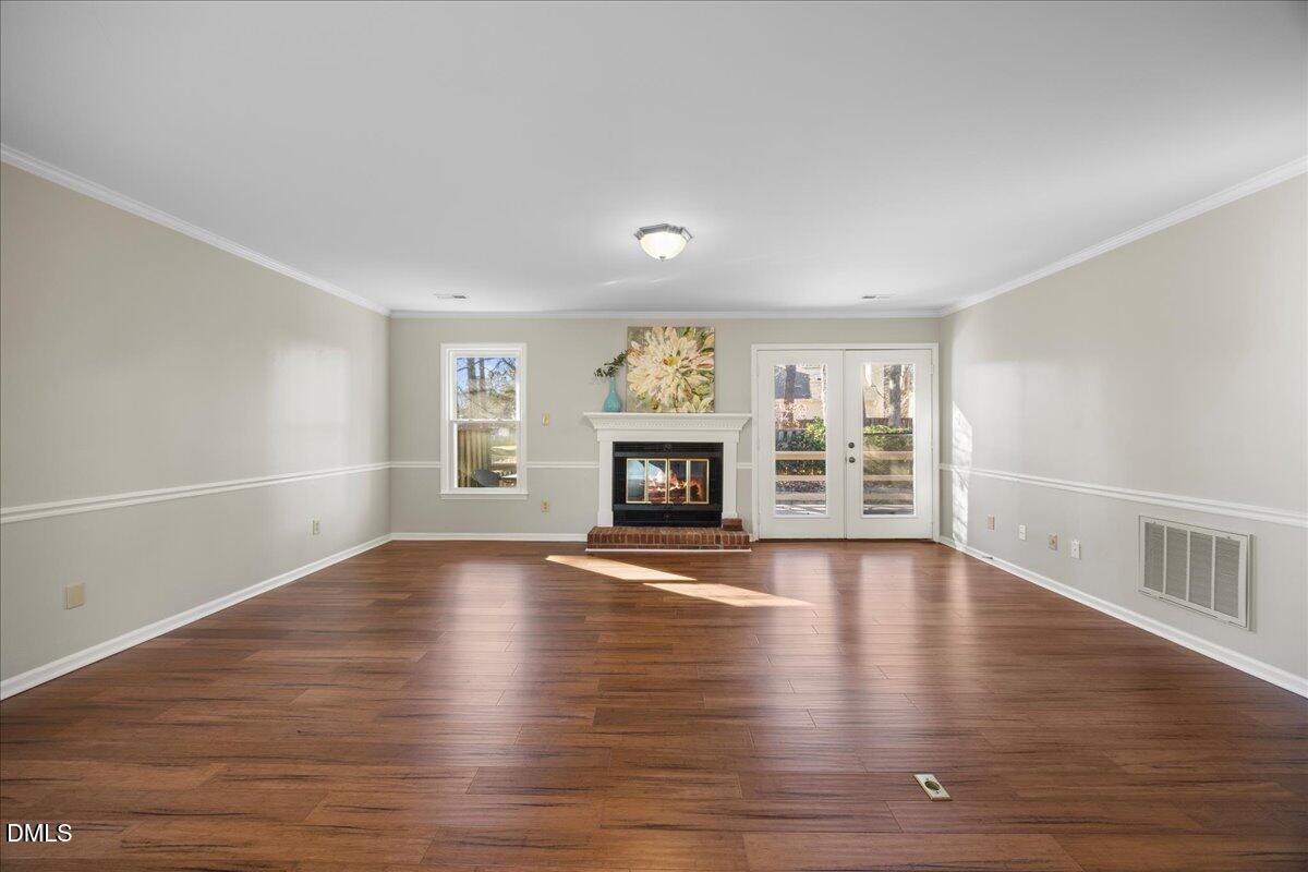 1511 Hemphill Drive Raleigh, NC 27609 - Photo 12 of 37 an empty room with wooden floor fireplace and windows