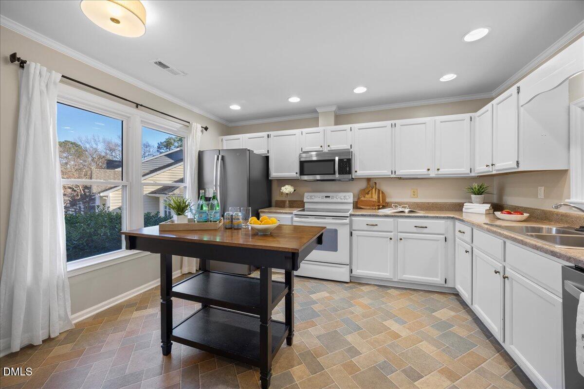 1511 Hemphill Drive Raleigh, NC 27609 - Photo 5 of 37 a kitchen with stainless steel appliances granite countertop a stove top oven a refrigerator a sink and white cabinets with wooden floor