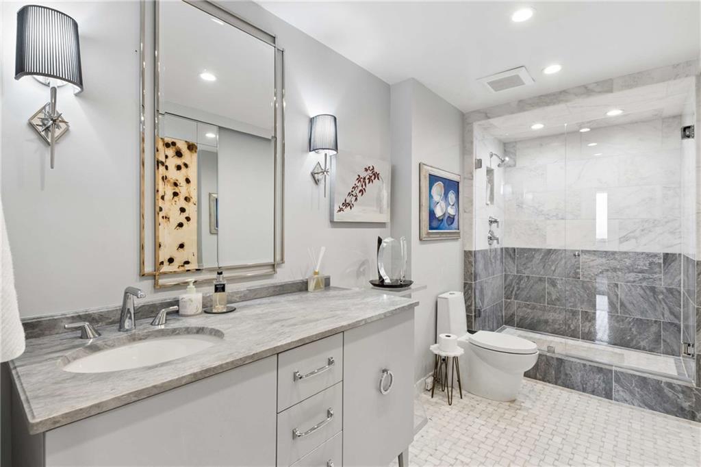 2660 Peachtree Road Northwest, Unit 34F Atlanta, GA 30305 - Photo 41 of 58 a bathroom with a granite countertop sink mirror vanity bathtub and a toilet