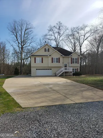 a front view of a house with a yard covered with trees